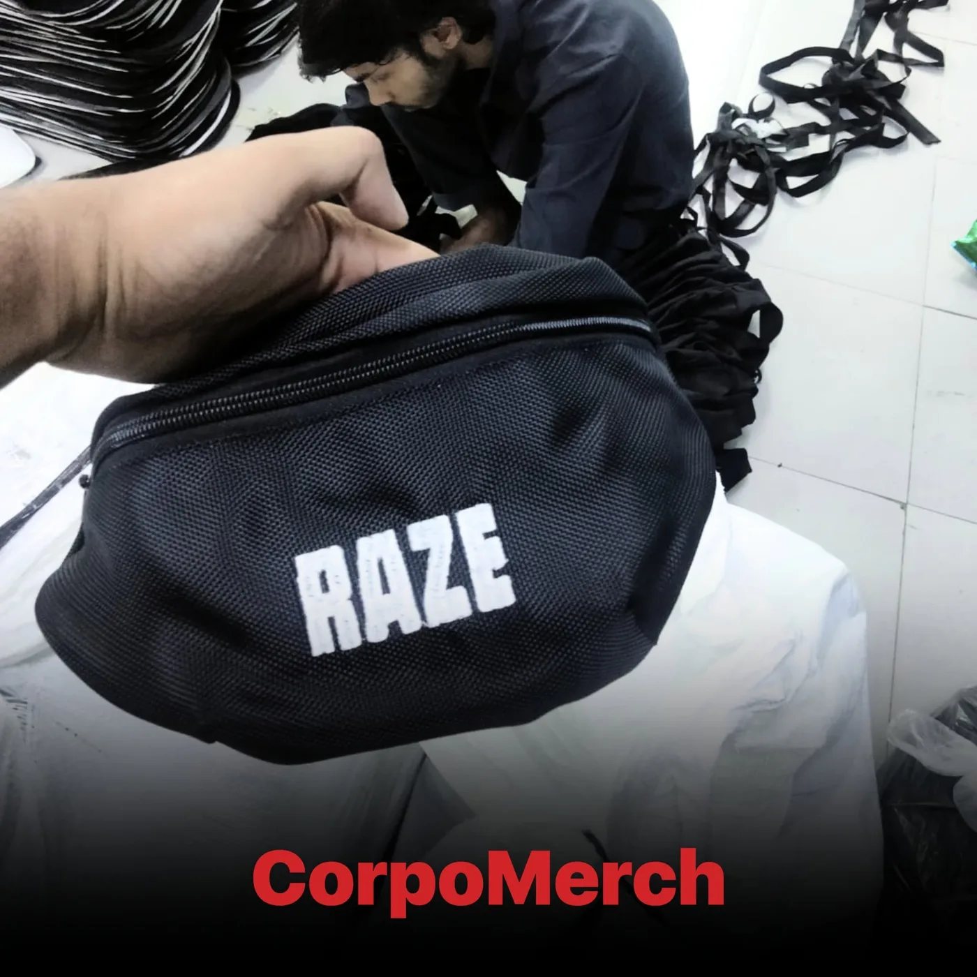 Black RAZE fanny pack with white printed logo being checked during quality control