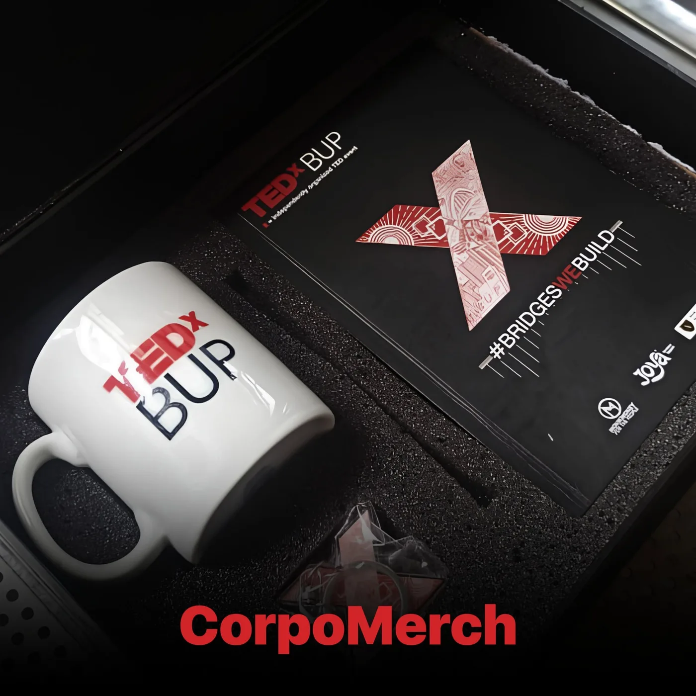 TEDxBUP custom gift box opened to show a printed ceramic mug and branded participant kit inside foam